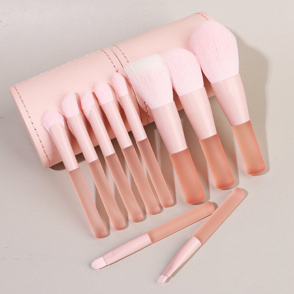 10 different pink makeup brushes in a pink cylindrical leather case packaging