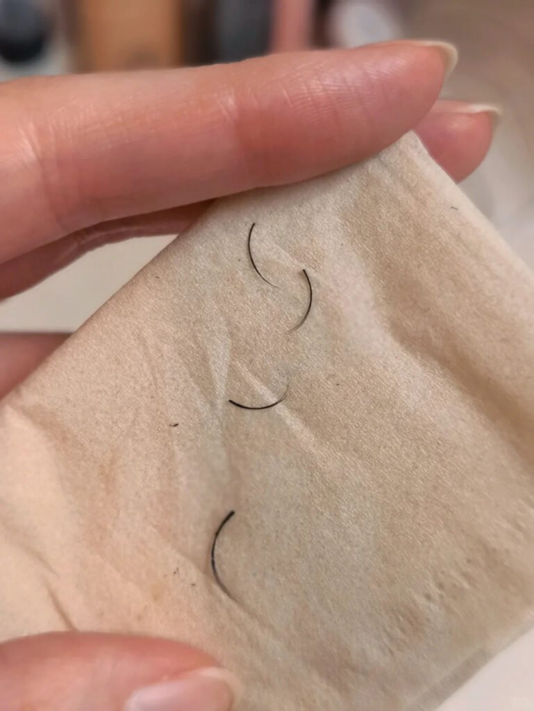 A hand holding removed eyelash extensions