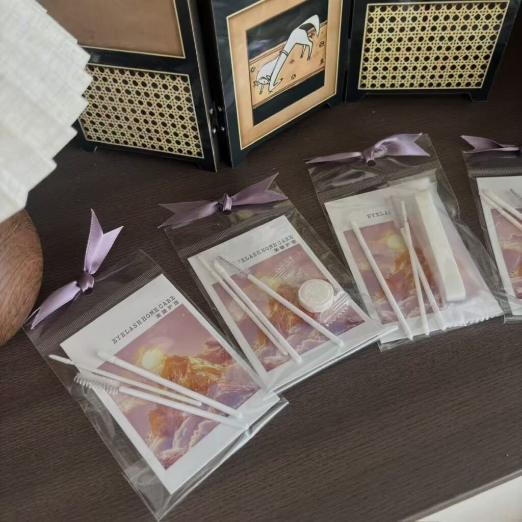 Shewincosmetic's Customizable Eyelash Extension Kit and Aftercare Kit with colorful patterned instruction cards, tied with a bow.