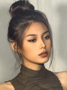Close-up side profile of a young woman with deep skin tone wearing light glam makeup, showcasing the dramatic length and flawless curl of Shewincosmetic's strip eyelashes for a voluminous eye-opening effect.