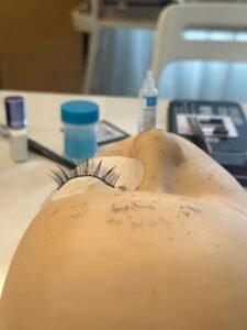 A student applying eyelash extensions on a practice mannequin head during an Eyelash Extension Training Course